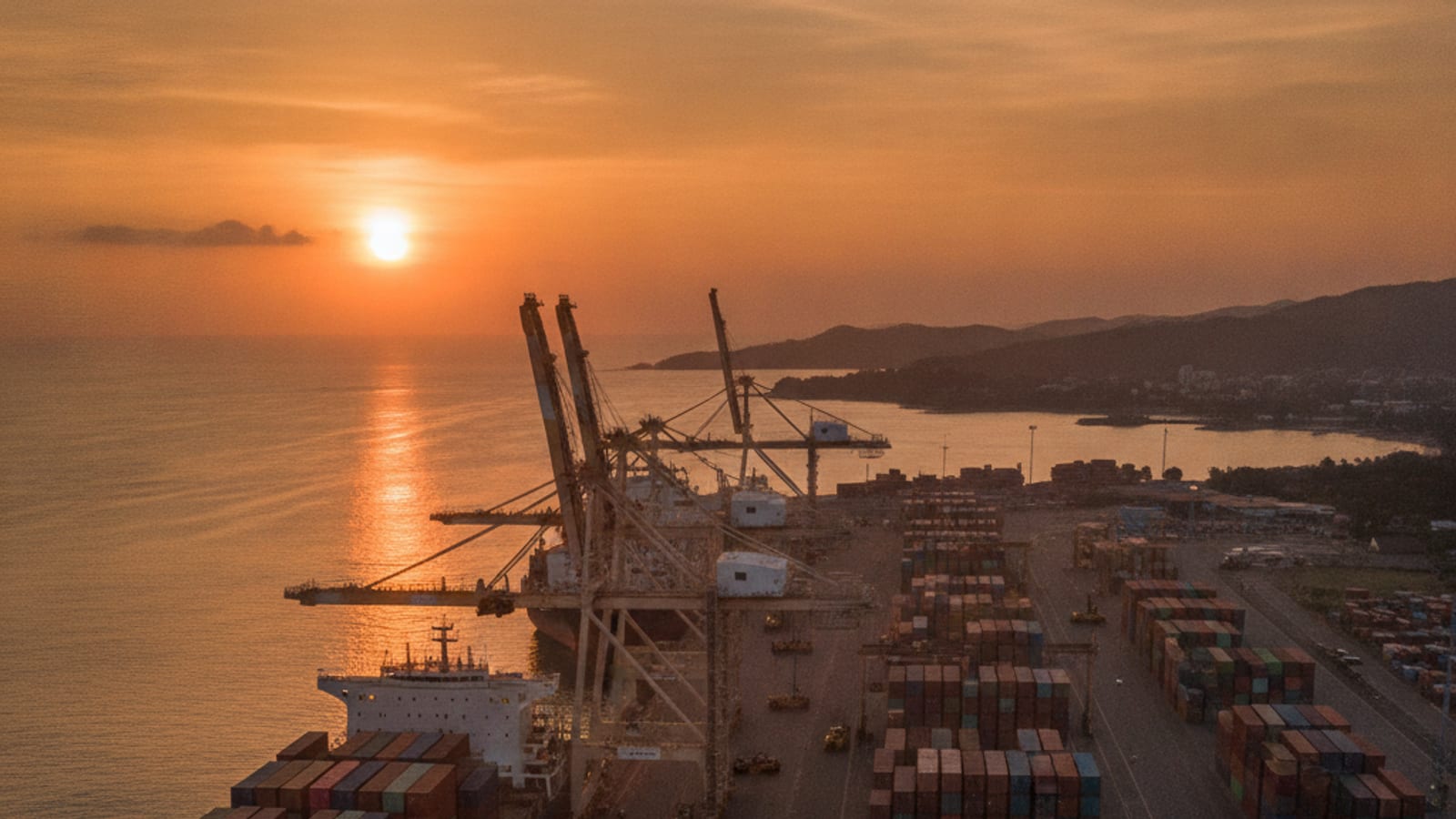 Cargo ships and containers at a busy port in Dili, Timor-Leste, at sunset.